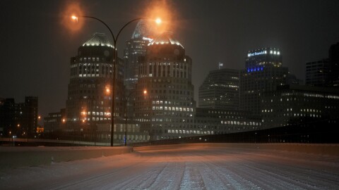 a snow covered road with a city skyline in the background, lit up at night