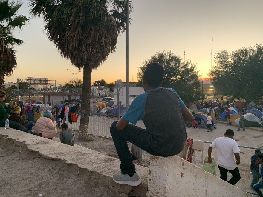 A young boy eats his meal that was delivered by Team Brownsville as he overlooks the encampment where many asylum seekers sleep. 