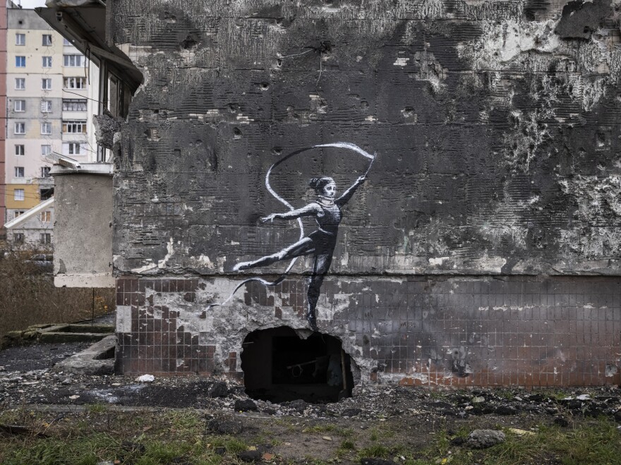 Graffiti of a woman in a leotard and a neck brace waving a ribbon is seen on the wall of a destroyed building in Irpin on Friday.