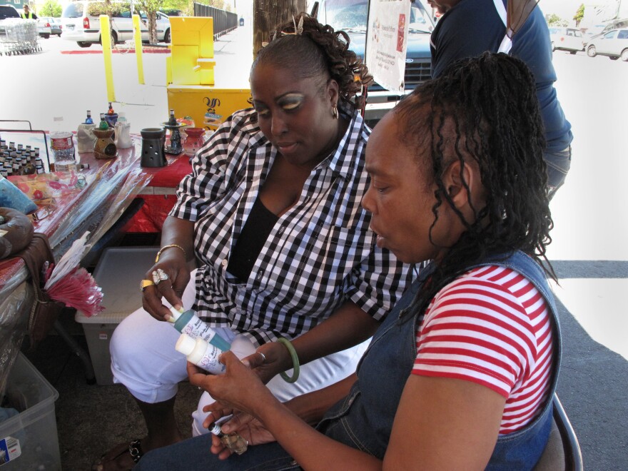 Yovanda Dixon (left) shows fellow group member Pamela Travis some of the bath oils she sells outside a San Francisco grocery store as part of her business Scentuality.