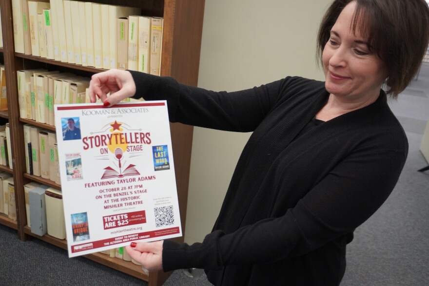 Jennifer Knisely, the executive director of the Altoona Area Public Library, holds a flyer for the upcoming "Storytellers on Stage" event at the Mishler Theatre. The event is October 28 at 7 p.m.