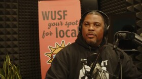 African American man sits by microphone with headphones on 