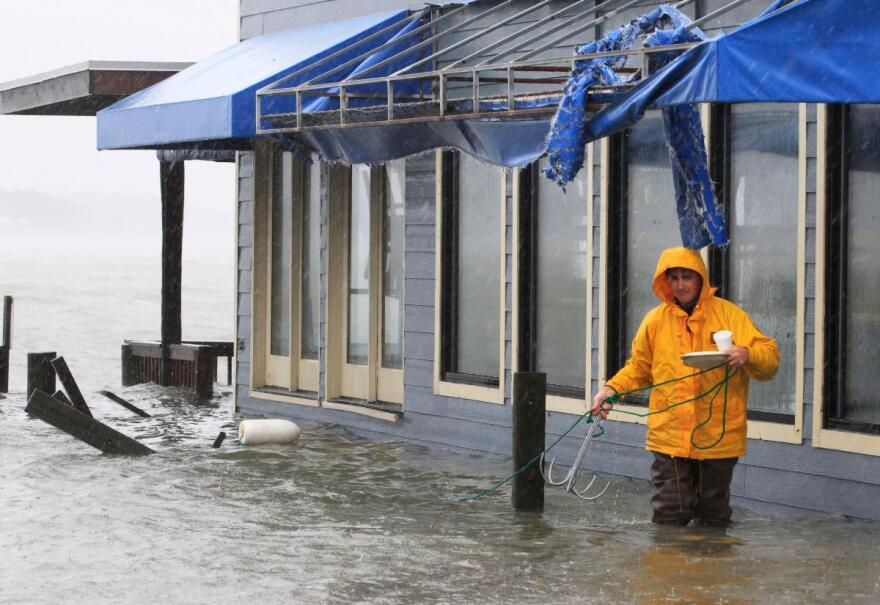 A worker retrieves a grappling hook on the dock next to Bubba’s restaurant on the water in Virginia Beach, Va., Monday, Oct. 29, 2012.