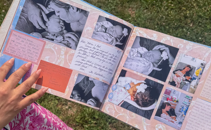a baby scrapbook with a person's manicured hand in the photo