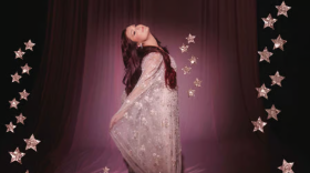 Woman with deep pink hair wearing a pink sparkly dress with stars around her 