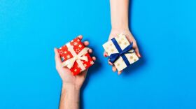 2 human hands holding small wrapped boxes with bows