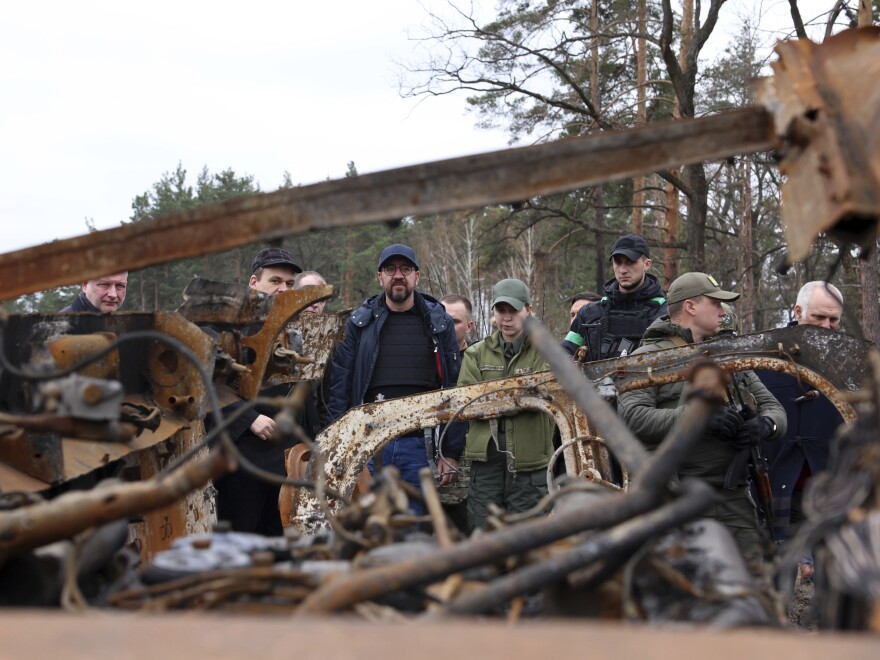 In this image provided by the European Council, European Council President Charles Michel, center, looks at destroyed vehicles as he is given a tour of the region of Borodyanka, Ukraine, Wednesday, April 20, 2022.