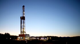 A natural gas drilling rig's lights shimmer in the evening light near Silt, Colo. Methane is the main component of natural gas, and studies show some methane escapes from leaky oil and gas operations.