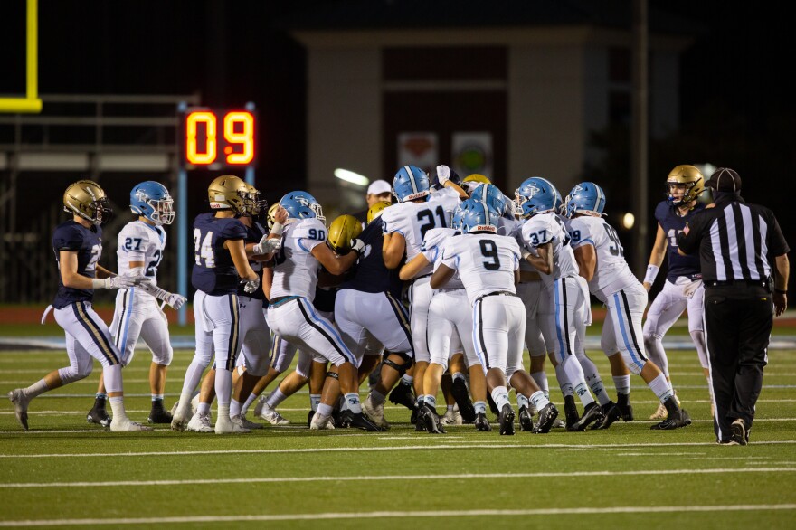 Players from both Spain Park and Briarwood swarm the ball carrier during a play late in the first half. Social distancing on the sidelines is emphasized but impossible on the field.