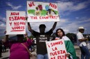 Artist Jonathan Martinez, 22, center, whose Mexican parents first worked on farms when they arrived in the U.S. more than two decades ago, holds a hand-painted sign as protests along with his sister Paola, right, a 19-year-old cosmetology student, against Florida Senate bill 1718, which imposes restrictions on undocumented immigrants, Thursday, June 1, 2023, in Immokalee, Fla.