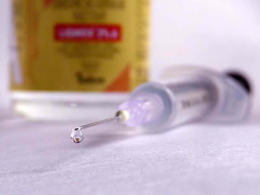 the point of a hypodermic needle is shown with a drop of liquid 