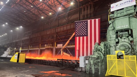a steel mill with a glow of molten steel making process with an american flag in the background