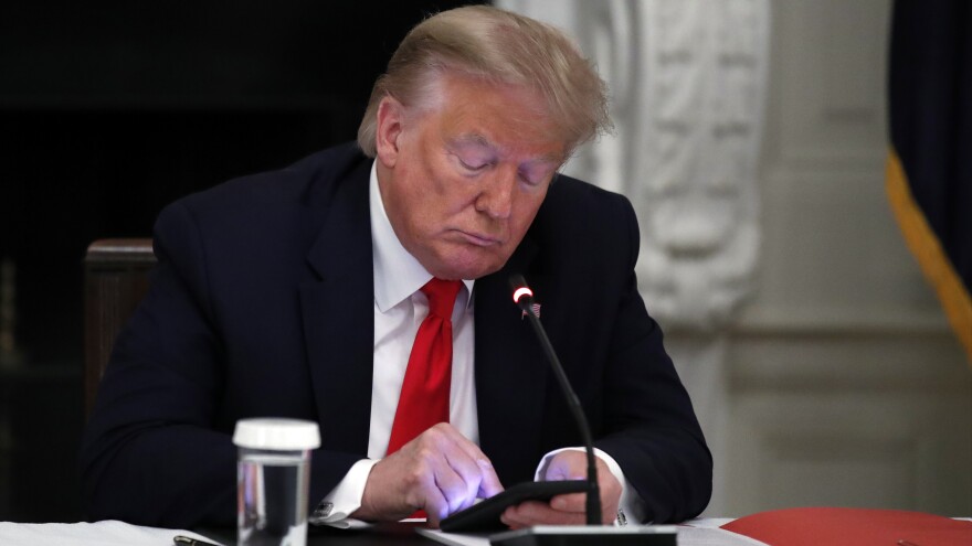 Former President Donald Trump looks at his phone during a roundtable with governors in the State Dining Room of the White House in Washington, June 18, 2020.