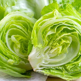 Fresh green iceberg lettuce salad leaves cut on light background on the table in the kitchen
