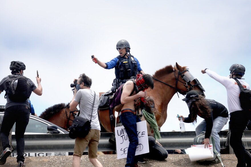 Mounted police officers use pepper spray on protesters attempting to get on Interstate 35 Saturday afternoon.