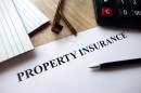 Property insurance document with pen, calculator and glasses on desk