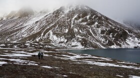 Two people walking beside a lake