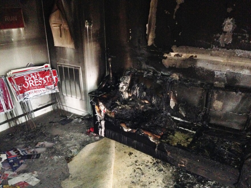 A burned couch rests next to warped campaign signs at the Orange County Republican Headquarters in Hillsborough, N.C.