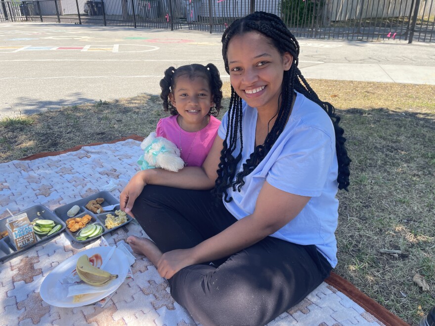 Catherine Ortiz eats lunch with her youngest of four children, Karielys, in Burnham Park on July 29, 2026. She and her family come to the park to receive free meals during the summer provided by Hunger Task Force.