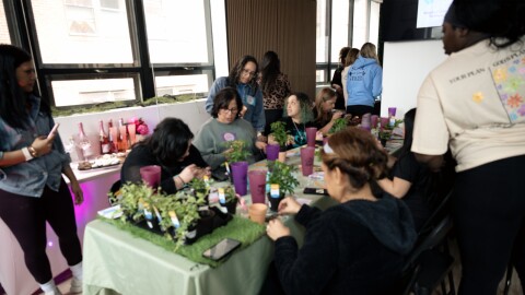 Participants in Respira Counseling and Wellness's self-care retreat on March 7, 2026 paint flower pots, as Respira founder Shasterin Valentin (standing, center) encourages the women to name their new plants after themselves as a reminder to take care of oneself as diligently.