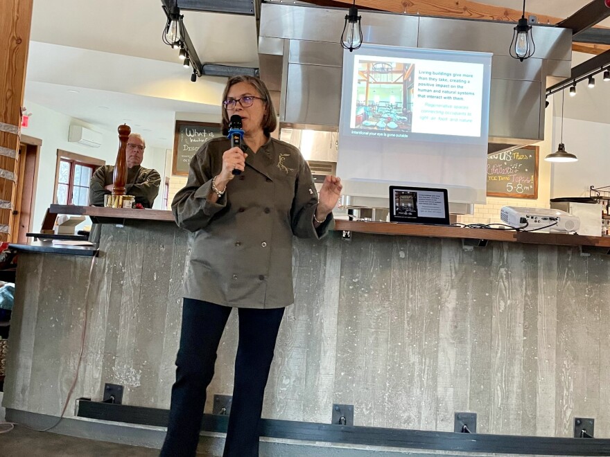 Monica Gastiger tells the class about RE Farm Café's sustainability efforts, while Duke Gastiger watches from the kitchen behind her.