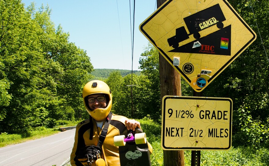 Jack Collins of Harrisburg, Pennsylvania, has been skating downhill for six years. Here he stands next to a road-grade sign on Whitcomb Hill Road in Florida, Massachusetts. 