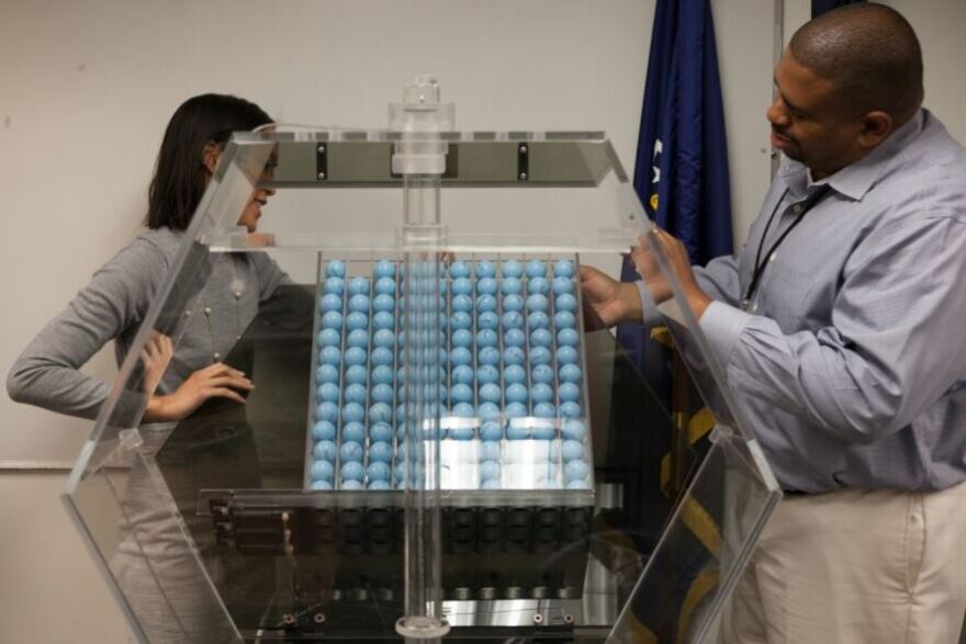 In a 2015 photo, Selective Service program analysts Vince McClure (right) and Cristine Nguyen demonstrate the machines that would determine who would be drafted if the U.S. reinstates a military draft.