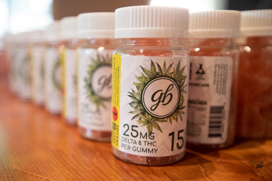 Bottles of gummies sit lined up on a counter. They have child-resistant lids and are clearly labeled as delta-8 THC gummies.
