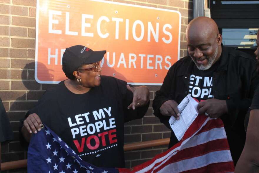 Desmond Meade (r) shows off his voter registration slip outside the Orange County Supervisor of Elections office. Photo: Emily Lang, WMFE