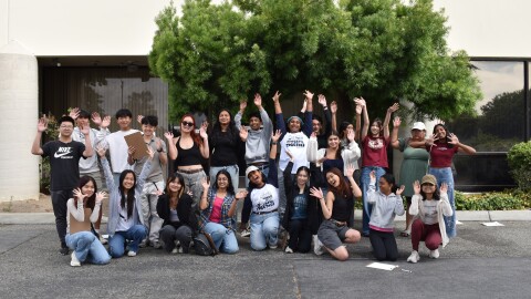 Members of the South Bay Youth Changemakers, all young people in casual clothing, pose cheerfully in front of a tree. 