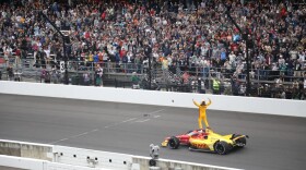 Alex Palou stands on his vehicle to the cheers of the crowd after winning the 109th running of the Indianapolis 500,