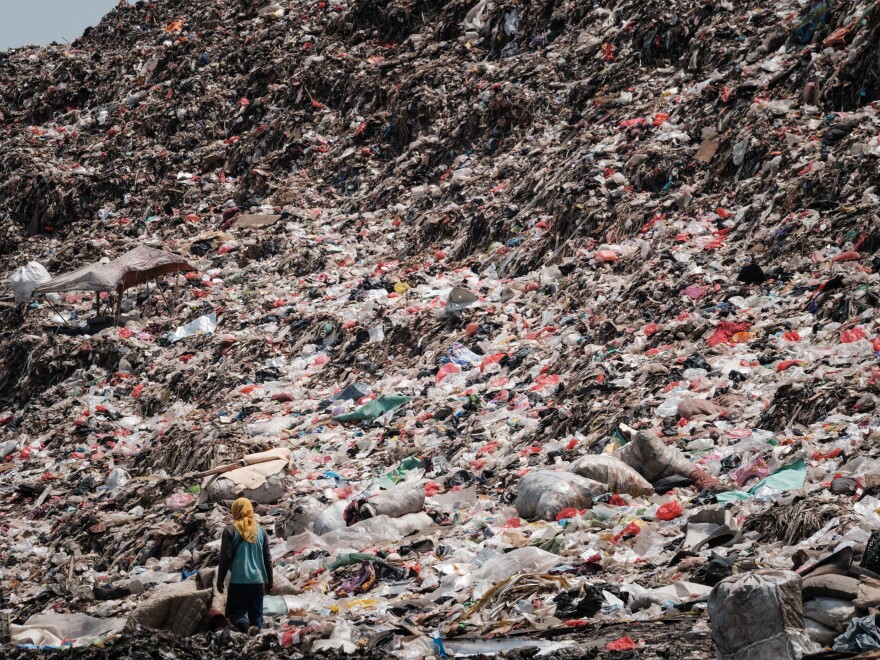 A registered scavenger, who mainly collects plastic waste to sell, walking in a landfill in Indonesia.