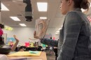 Girl holds book up for class to see. 