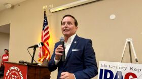 A man in a blue suit is holding a microphone at a podium.