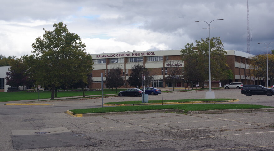 Kalamazoo Central High School is pictured on October 16, 2026. It is a red brick building with cream accents, and a large maroon sign reading "Kalamazoo Central High School" a few cars are parked in the parking lot in front of the school, and it is a grey and cloudy day. 