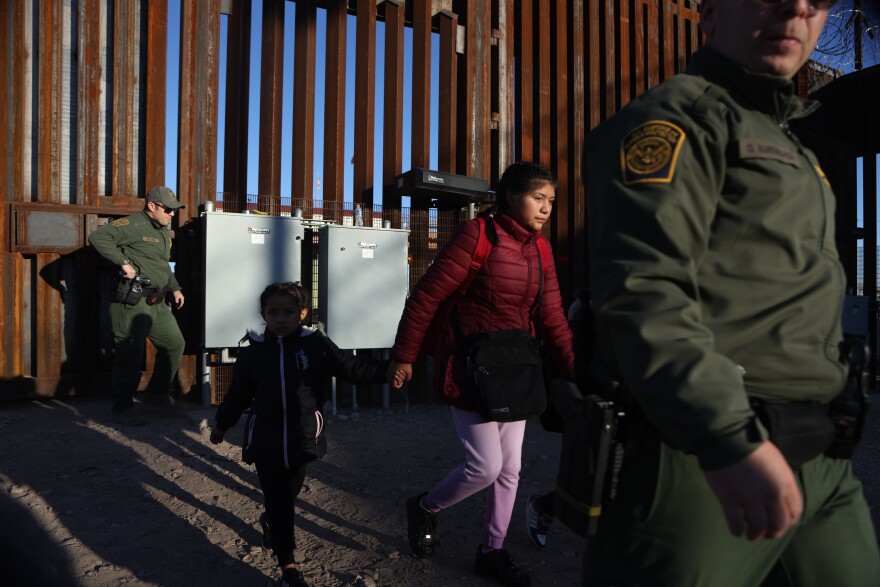 Three unaccompanied minor asylum-seeking migrant children are escorted through the border wall to be processed by U.S. Customs and Border Protection after crossing the Rio Grande River into the United States in El Paso, Texas, U.S., December 21, 2022.