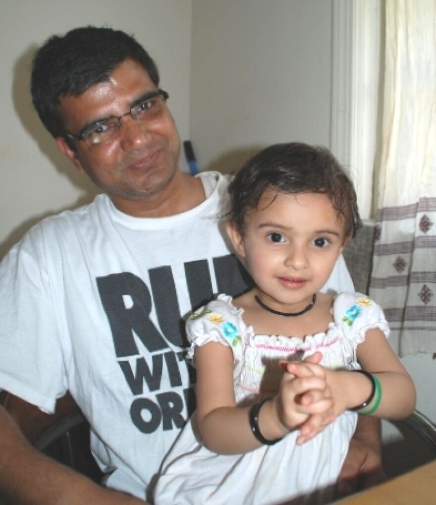 Sitting in her father's lap, Diya offers the Hindu greeting of  <em>Namaste</em>