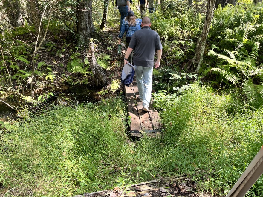 A group walks over a make-shift railroad tie bridge to learn about the newest piece of land added to the Pinchot State Forest in Scranton.