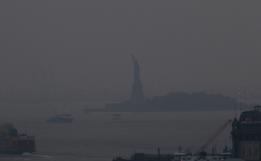 The Staten Island Ferry departs from the Manhattan terminal through a haze of smoke from Western wildfires, with the Statue of Liberty barely visible on Tuesday, July 20, 2021.
