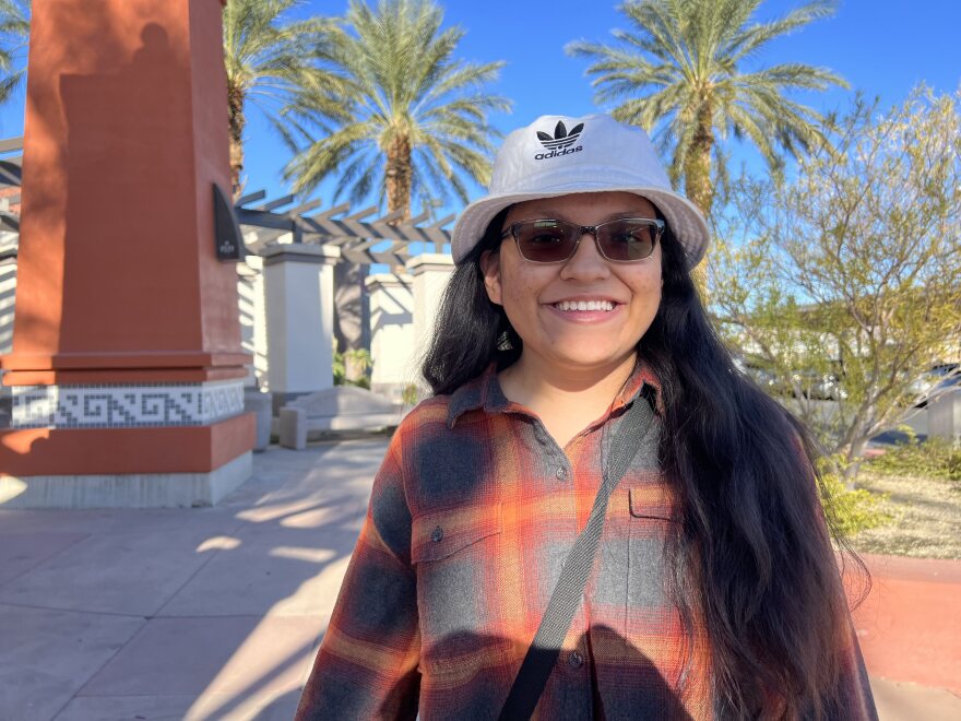 Ketzia Jimenez smiles for a photo outdoors. It’s sunny and there are palm trees behind her.