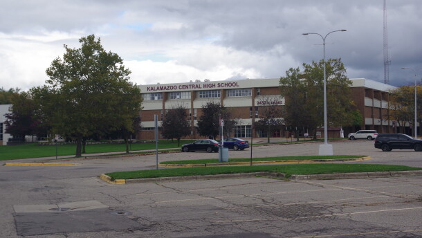 Kalamazoo Central High School is pictured on October 16, 2026. It is a red brick building with cream accents, and a large maroon sign reading "Kalamazoo Central High School" a few cars are parked in the parking lot in front of the school, and it is a grey and cloudy day. 