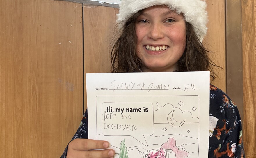 Fifth-grader Sawyer poses with their winning drawing of Dora the Destroyer.