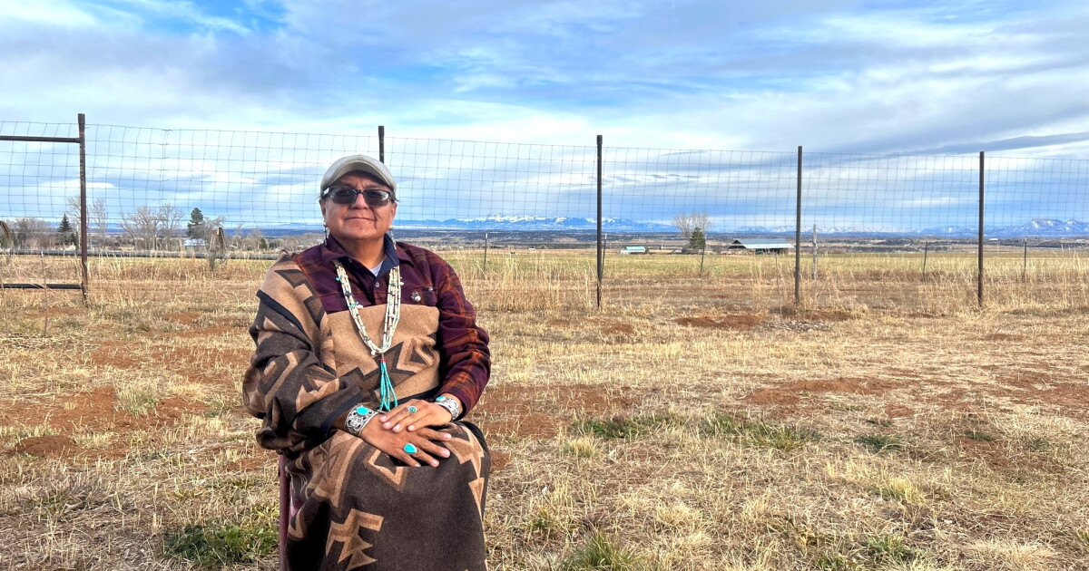 A weaver in traditional dress stands in a high-desert pasture on the Navajo Nation