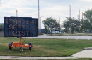 A large electronic sign on wheels placed in a grassy area next to a parking lot. The sign reads 'Starting Sept. 21st.' 