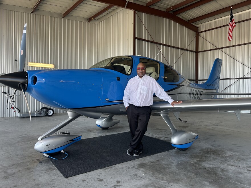 Patrick Nelson, Red Tail Academy's Executive Director, stands on the side of a Cirrus SR22, one of five planes in the Academy's inventory.