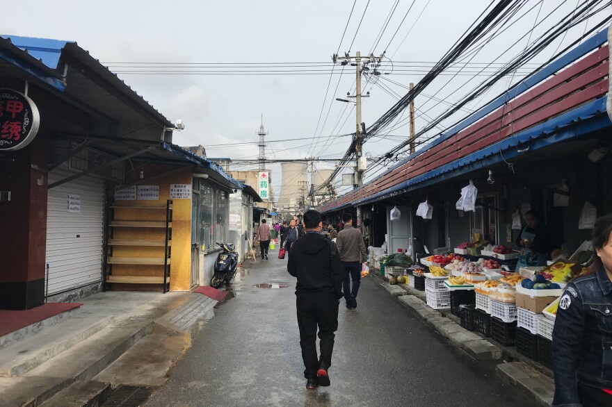 People shop for groceries in a market in the shadow of the Huaneng Beijing Terminal Power Plant. Local restaurant owners and shopkeepers say the air around the power plant has been cleaner since it switched to natural gas from burning coal in recent years.