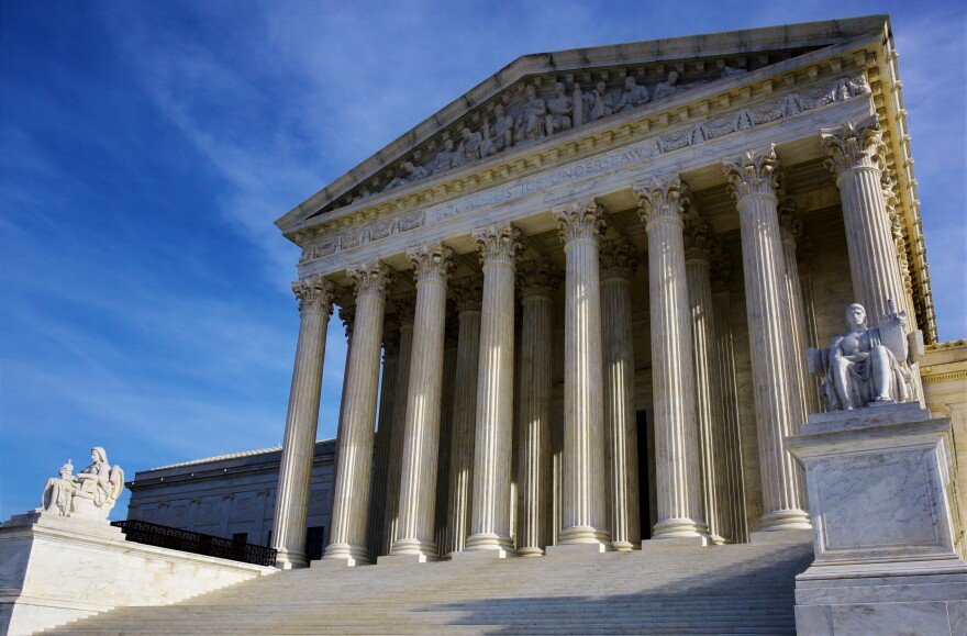 The front exterior of the United States Supreme Court building in Washington, D.C. Its entrance has eight, tall columns at the top of a set of stairs.
