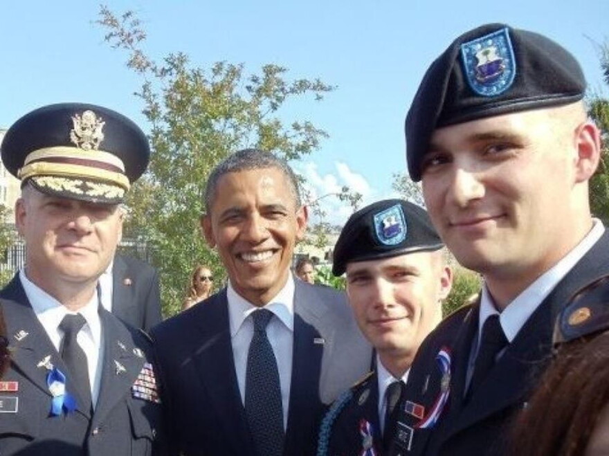 A photo of four men. Three are wearing military gear.