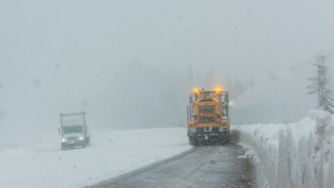 A snowplow clears a few inches of snow off a road