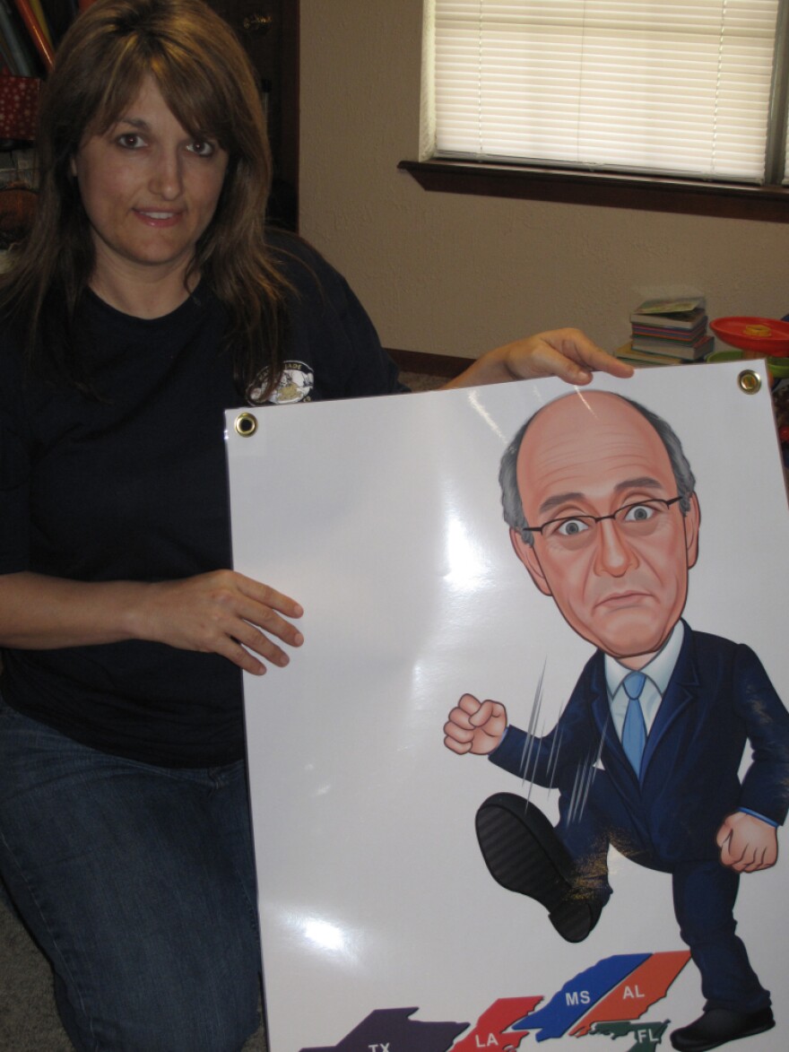 Kim Chauvin holds a poster of oil spill claims czar Kenneth Feinberg stomping on the Gulf Coast, a decoration on her family's boat. She is frustrated that their claim hasn't been paid.